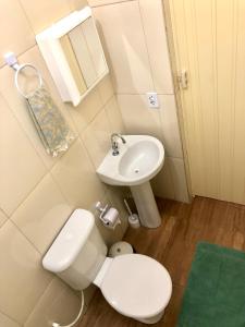 a bathroom with a white toilet and a sink at Vila do Surfe in Ubatuba