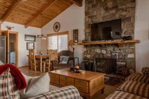 a living room with a stone fireplace with a tv at Hot tub*kids room*family cabin in Big Bear City