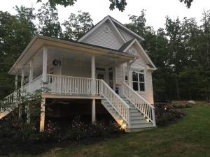 a small white house with a porch and stairs at Primrose Cottage - Private Lake, Hot Tub, ATV Trails in Mena