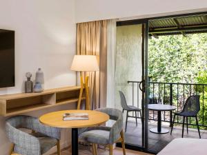 a room with a table and chairs and a balcony at Mercure Darwin Airport Resort in Darwin