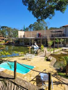 a pool with tables and chairs in front of a building at Lago e Lazer in São Roque