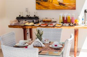 una mesa con sillas y una mesa con comida. en Caly Pousada, en São Miguel do Gostoso