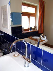 baño con lavabo y pared de azulejos azules en Bio Pension Kirschenfee, en Sontheim