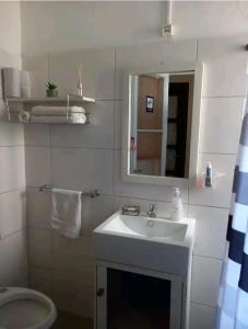 uma casa de banho branca com um lavatório e um espelho em Cálido apartamento a 8 cuadras del mar y a 3 de 18 Julio Hay una gatita que vive allí em Montevidéu