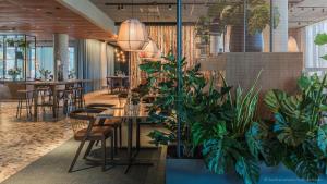 a restaurant with potted plants and tables and chairs at Quality Hotel The Weaver in Gothenburg