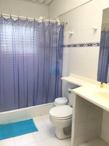 a bathroom with a toilet and a blue shower curtain at Casa de campo mesitas del colegio in El Colegio