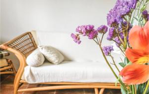 a couch with pillows and purple flowers in a vase at Awesome Home In Jedwabno With House Sea View in Jedwabno