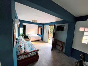 a blue room with a bed and a couch at Studio Taípe Arraial in Porto Seguro