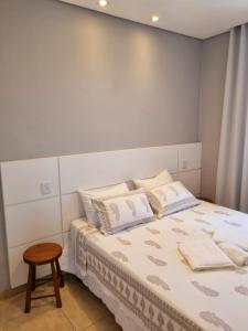 a bedroom with a bed and a stool at Apartamento ao lado da UFOP com garagem in Ouro Preto