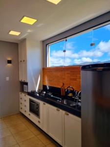a kitchen with a large window and a sink at Apartamento ao lado da UFOP com garagem in Ouro Preto