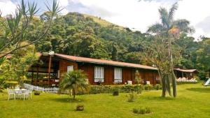 una casa frente a una montaña con un patio de césped en Chalé Canoas - Conforto na serra de Teresópolis en Teresópolis