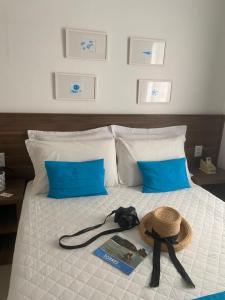 a hat and a book on a bed with blue pillows at Pousada Natália in Torres