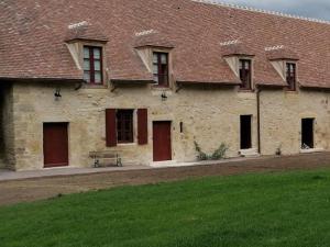 ein altes Steingebäude mit roten Türen und einem grünen Feld in der Unterkunft Gîte Ainay-le-Vieil, 5 pièces, 8 personnes - FR-1-586-15 in Ainay-le-Vieil