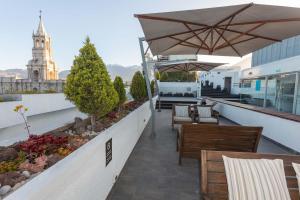 a rooftop patio with tables and chairs and an umbrella at Casa Andina Select Arequipa Plaza in Arequipa