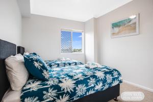 a bedroom with a bed with a blue blanket at Suttons Beach Apartments in Redcliffe