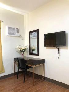 a room with a desk with a television and a mirror at Meaco Royal Hotel- Aparri in Camalaniugan