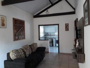 a living room with a black couch and a kitchen at Sítio Vista da Serra in Lavrinhas