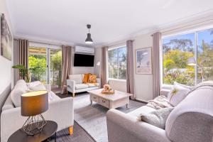 a living room with white furniture and large windows at Spring Cottage in Nowra