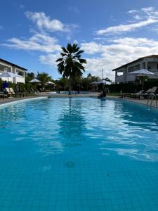 a large swimming pool with a palm tree in the background at Pérola do Tree Bies Resort in Entre Rios +25 photos