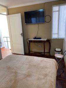 a bedroom with a bed and a tv on the wall at La Negrita Host in Sucre