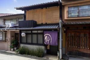 une maison avec une porte et une bannière violette sur elle dans l'établissement Rinn Tenjincho, à Kyoto