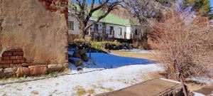 una casa con neve sul terreno accanto a un edificio di Den Hagen Guest Farm a Rhodes