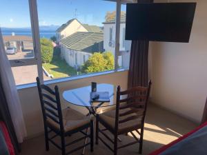 a table and chairs in a room with a large window at Absolute Lake View Motel in Taupo