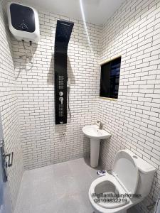 - une salle de bains avec un téléphone sur le mur à côté des toilettes dans l'établissement Gillant Luxury Homes, à Benin City
