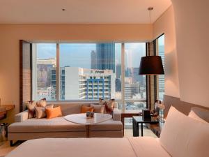 a living room with a couch and a large window at Le Meridien Bangkok in Bangkok