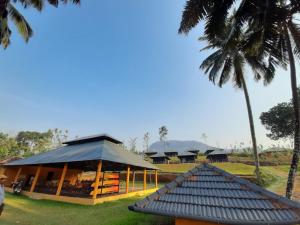 a building with a black roof and a palm tree at Birds Murmur Camp, Thattekkad in Cochin