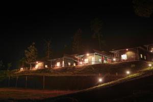 a house with lights on a hill at night at Birds Murmur Camp, Thattekkad in Cochin