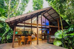 a small house with glass doors and wooden tables and chairs at Daintree Wilderness Lodge in Daintree