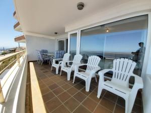 Un balcón con sillas y mesas blancas y vistas al océano. en Edificio Undurraga, en Viña del Mar