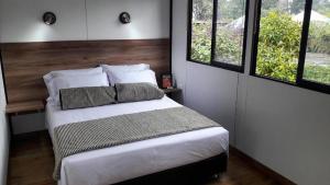 a bedroom with a bed with two pillows and two windows at STAR HOTEL & CLUB DE TENIS, a 2 pasos del Aeropuerto JMC, Transporte Incluido in Rionegro