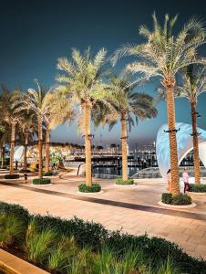 a row of palm trees on a sidewalk at Modern Urban 3 bedroom apartment Dubai Creek Harbour in Dubai