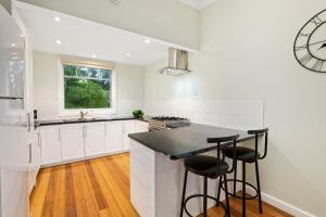 a kitchen with white cabinets and a black counter top at Paddys Creek Retreat in Upwey