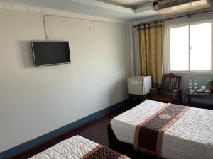 a hotel room with two beds and a tv on the wall at Mekong Hotel in Ban Nabông