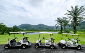 two golf carts parked next to a golf course at Tinidee Golf Resort Phuket - SHA Extra Plus in Kathu