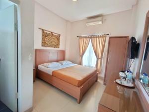 1 dormitorio con 1 cama y TV en The Sriwijaya Hotel - Halal Hotel, en Padang