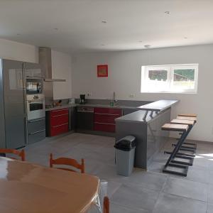 a large kitchen with red cabinets and a table in it at Le domaine de l'Ebenne in Englefontaine