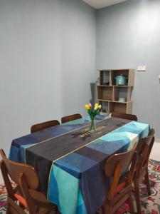 a dining room table with a vase of flowers on it at D'Nenas Homestay Kijal in Kijal