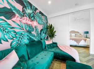 ein Wohnzimmer mit einer grünen Couch und einem Wandbild aus Blättern in der Unterkunft Lusso Retreats in Moffatdale