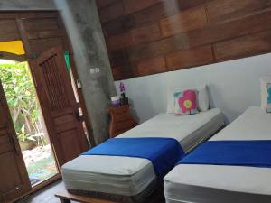 a bedroom with two beds and a door to a yard at Watukarung Ristu Homestay in Kalak