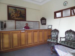 a man sitting at a cash register in a waiting room at Sukapura Permai Hotel in Lambangkuning