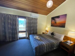 a bedroom with a bed and a large window at Mountain Creek Motel Bar & Restaurant in Mount Beauty