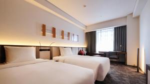 仙台市にあるANA　ホリデイ・イン仙台のベッド2台とデスクが備わるホテルルームです。