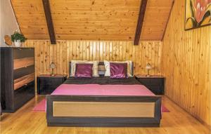 UktaにあるGorgeous Home In Ruciane-nida With Saunaの木製の壁のベッドルーム1室(大型ベッド1台付)