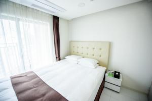 a bedroom with a white bed and a window at Hotel STAYON in Geoje 