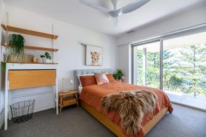 um quarto com uma cama e uma grande janela em Spectacular Bilgola Beachhouse em Avalon