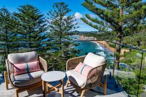 two chairs and a table on a balcony with a view of the ocean at Spectacular Bilgola Beachhouse in Avalon